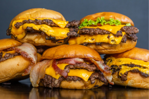 A bunch of delicious looking burgers piled up.