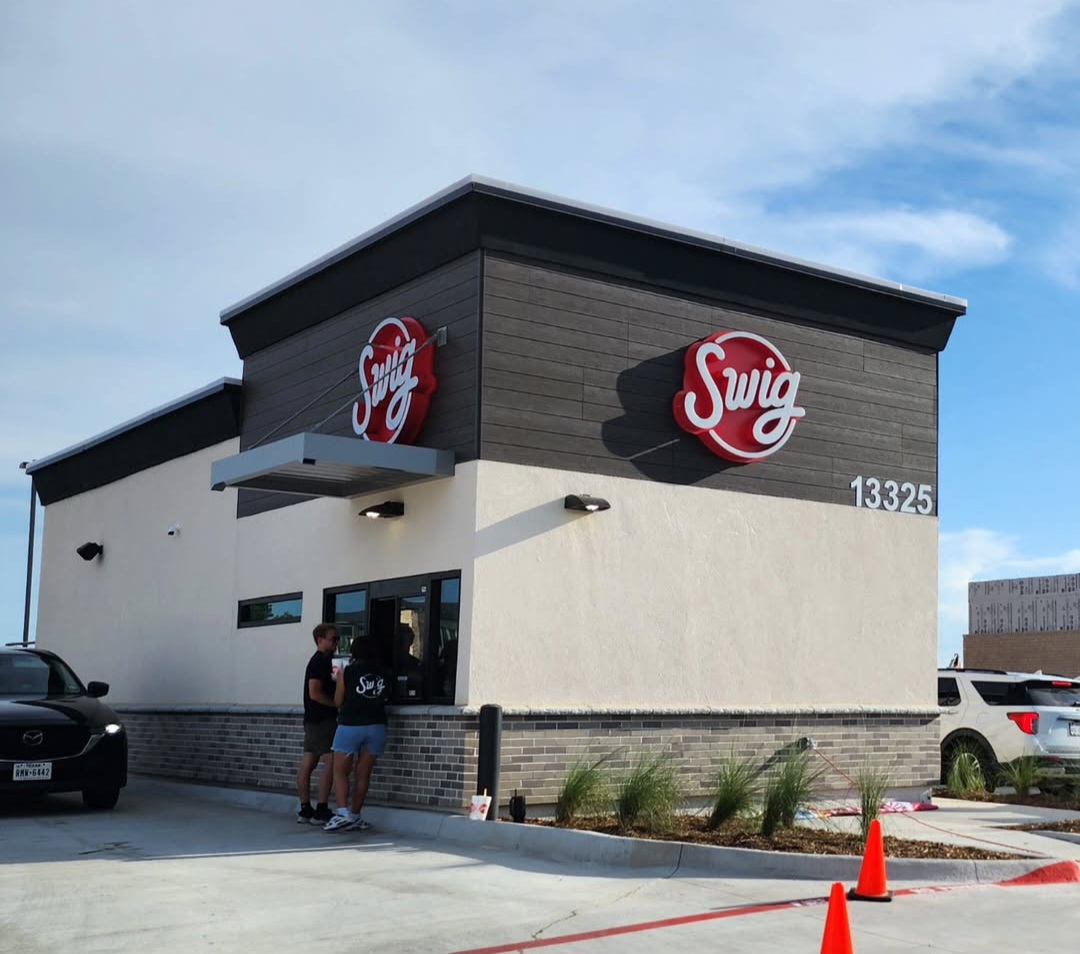 A Swig drive-thru location with a modern exterior, featuring the signature red logo above a service window