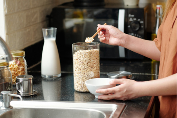 A person adding quick oats in a bowl