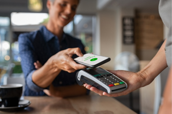 Customer using a smartphone to make a contactless payment, illustrating the question, 'Does Raising Cane's Take Apple Pay?